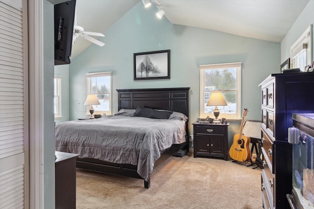 carpeted bedroom with ceiling fan, lofted ceiling, rail lighting, and multiple windows