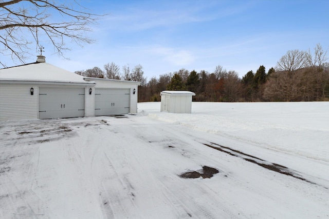 yard covered in snow with an outbuilding and a garage