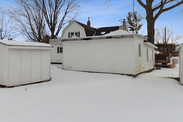 view of snow covered exterior with a balcony and a storage unit