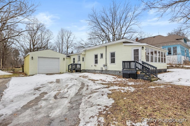 snow covered property with an outbuilding, a chimney, and a detached garage