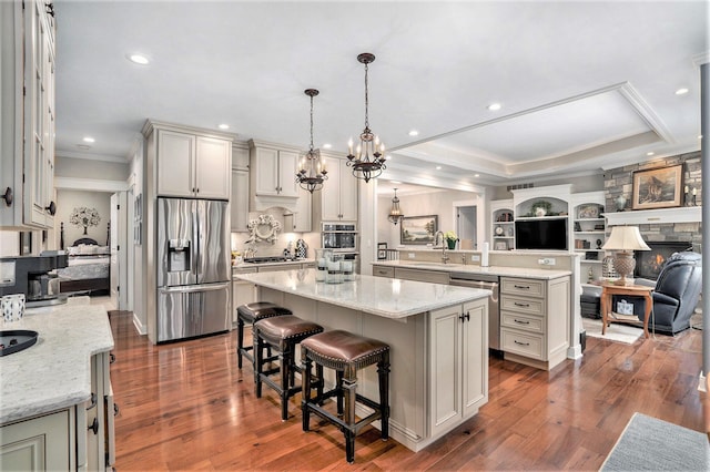 kitchen featuring appliances with stainless steel finishes, a breakfast bar, hanging light fixtures, a center island, and a raised ceiling