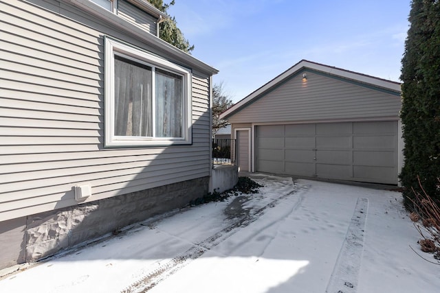 view of snow covered exterior featuring an outbuilding and a garage