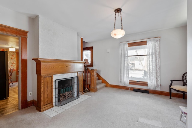 unfurnished living room featuring a tiled fireplace and light colored carpet