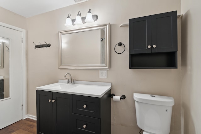 bathroom with hardwood / wood-style flooring, vanity, and toilet