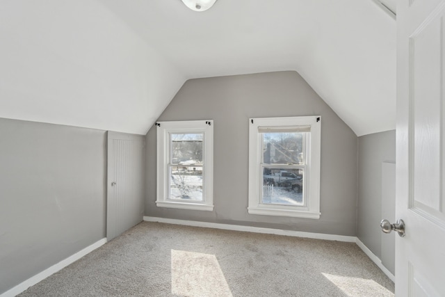 additional living space with a healthy amount of sunlight, vaulted ceiling, and light carpet