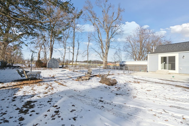 snowy yard with a storage shed