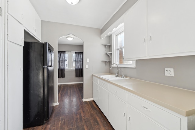 kitchen featuring dark hardwood / wood-style floors, a wealth of natural light, sink, white cabinets, and black fridge