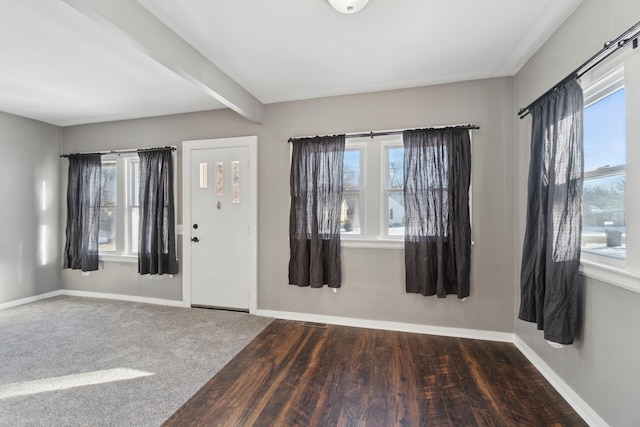 carpeted foyer featuring beam ceiling and a healthy amount of sunlight