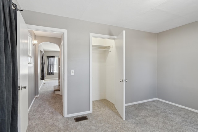 unfurnished bedroom featuring a spacious closet, light colored carpet, and a closet