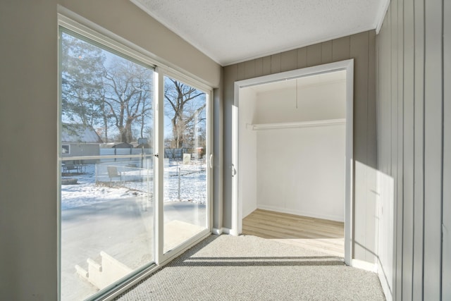 doorway to outside featuring light carpet and a textured ceiling