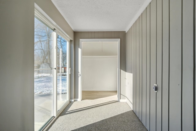 hall with wooden walls and a textured ceiling