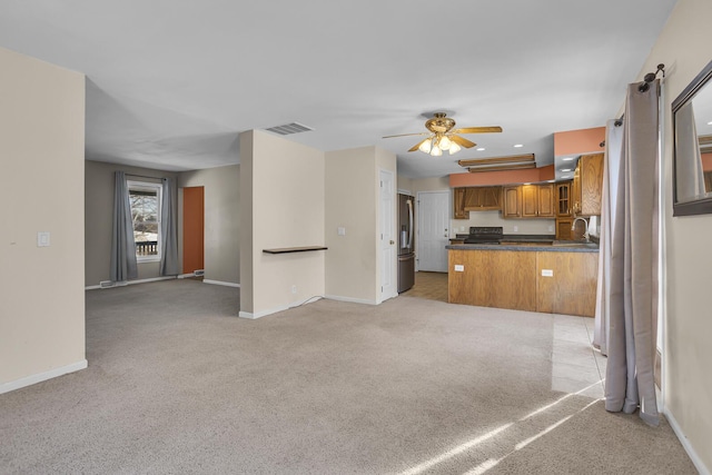 unfurnished living room featuring ceiling fan, sink, and light carpet