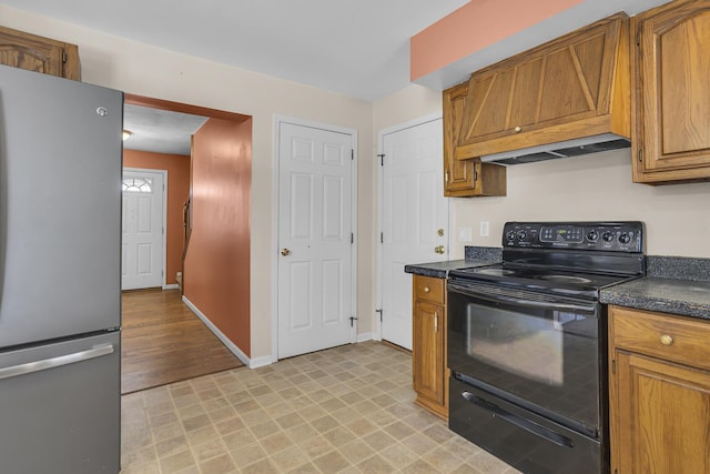 kitchen with black range with electric stovetop, premium range hood, and stainless steel fridge