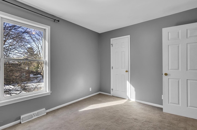 empty room with light colored carpet and plenty of natural light