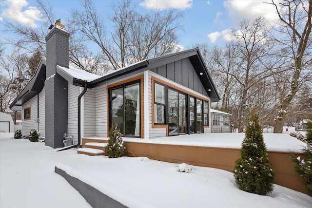 24112 N Shore Dr, Edwardsburg, MI 49112 - view of snowy exterior featuring a sunroom, a chimney, and a garage
