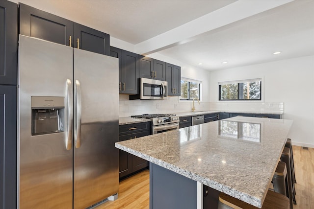 24112 N Shore Dr, Edwardsburg, MI 49112 - kitchen with light wood-style floors, decorative backsplash, a kitchen bar, and stainless steel appliances