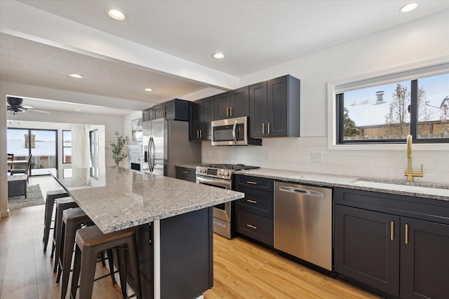 24112 N Shore Dr, Edwardsburg, MI 49112 - kitchen featuring light stone counters, a sink, a kitchen bar, stainless steel appliances, and decorative backsplash