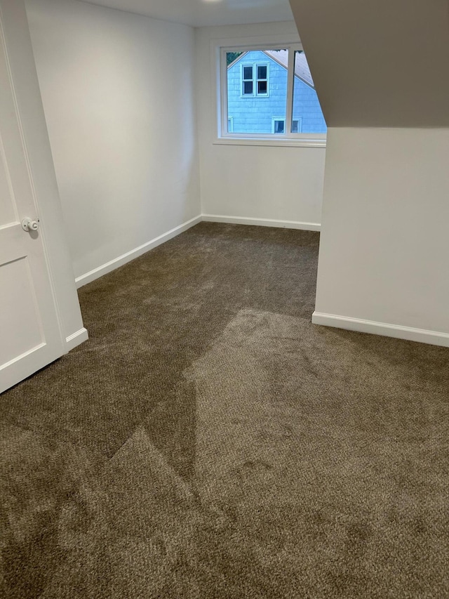 interior space featuring lofted ceiling and dark carpet