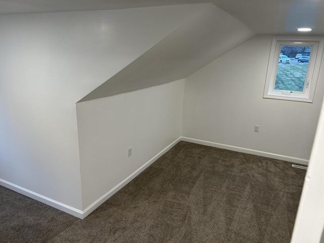 bonus room with vaulted ceiling and dark colored carpet