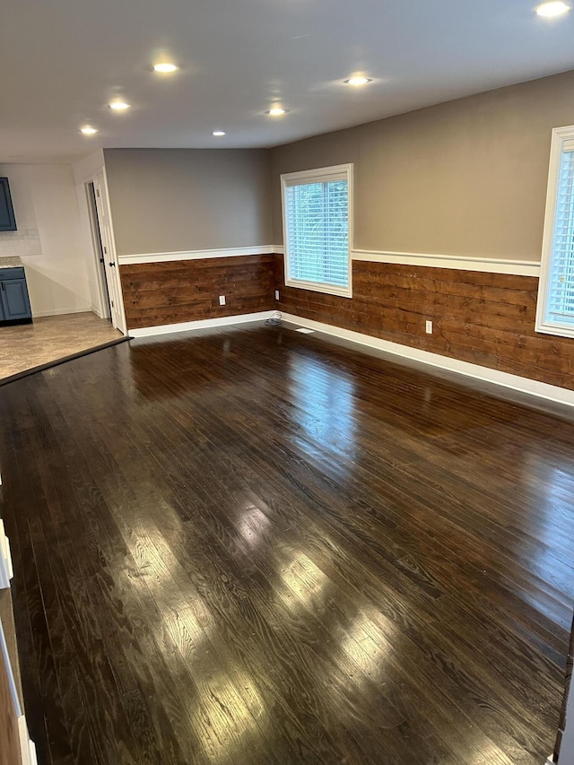 unfurnished room with dark wood-type flooring and wooden walls