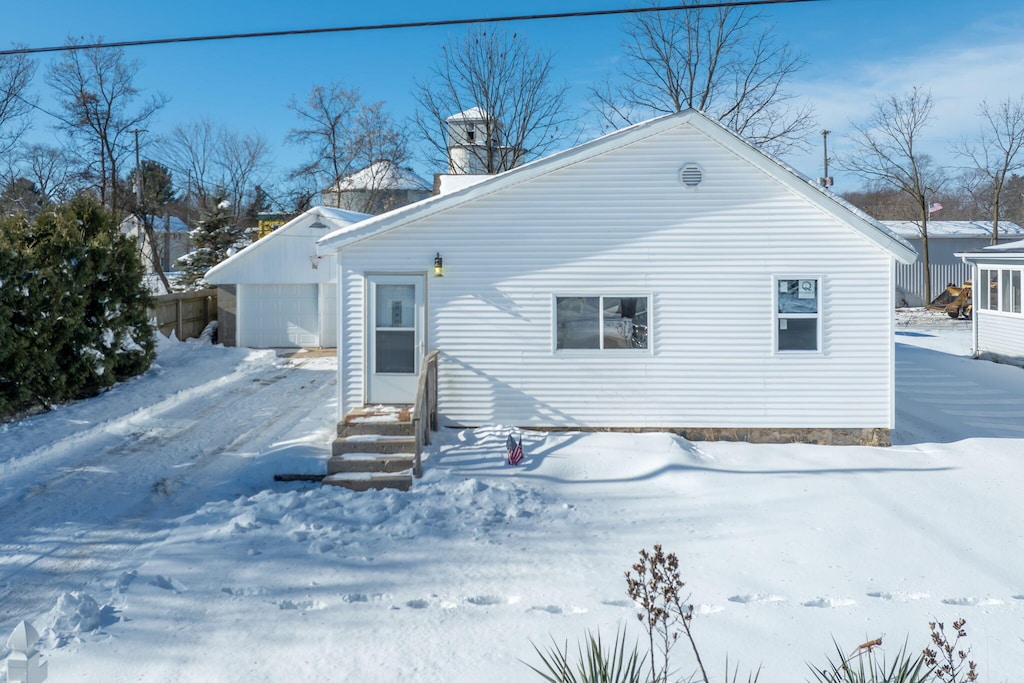 snow covered rear of property with a garage