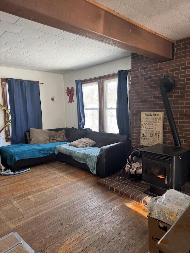 living room with dark hardwood / wood-style floors, beamed ceiling, and a wood stove