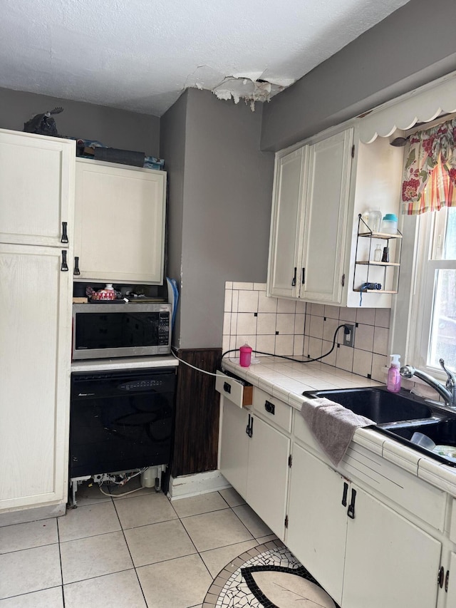 kitchen featuring oven, white cabinets, decorative backsplash, tile counters, and light tile patterned floors