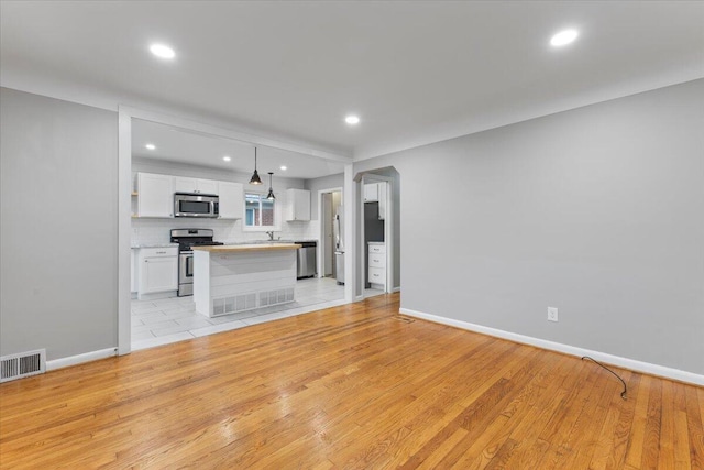 unfurnished living room featuring sink and light hardwood / wood-style floors