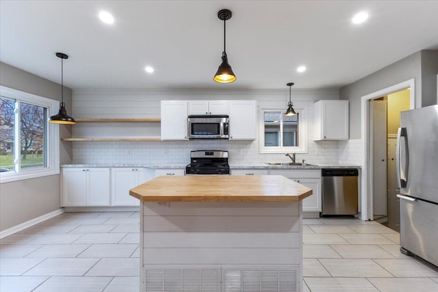 kitchen featuring pendant lighting, sink, stainless steel appliances, a center island, and white cabinets