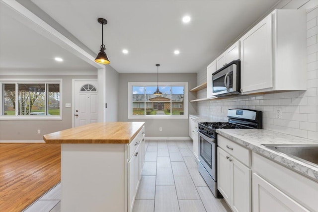 kitchen with stainless steel appliances, white cabinetry, and a center island