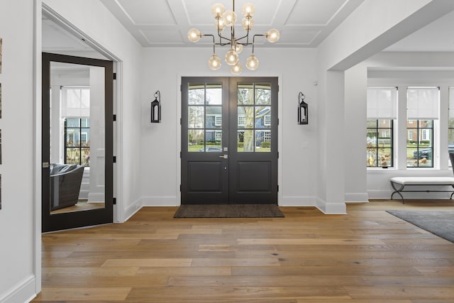 entrance foyer featuring light wood finished floors, baseboards, coffered ceiling, and french doors