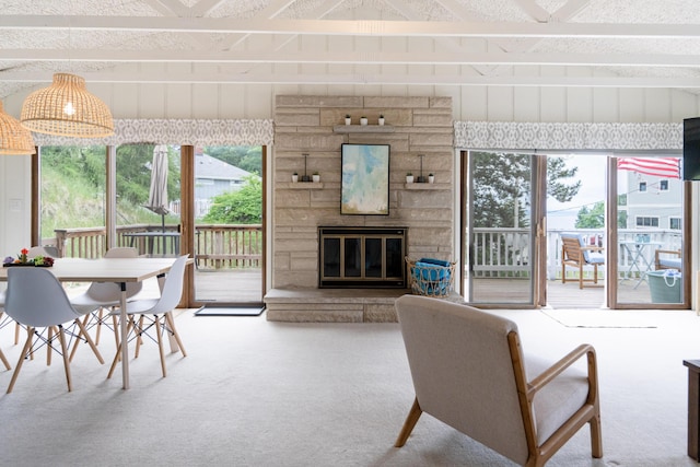 living room with a stone fireplace, carpet floors, and a wealth of natural light