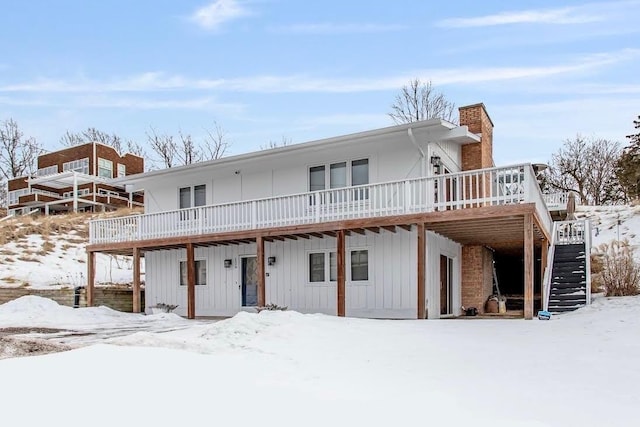 snow covered rear of property with a deck