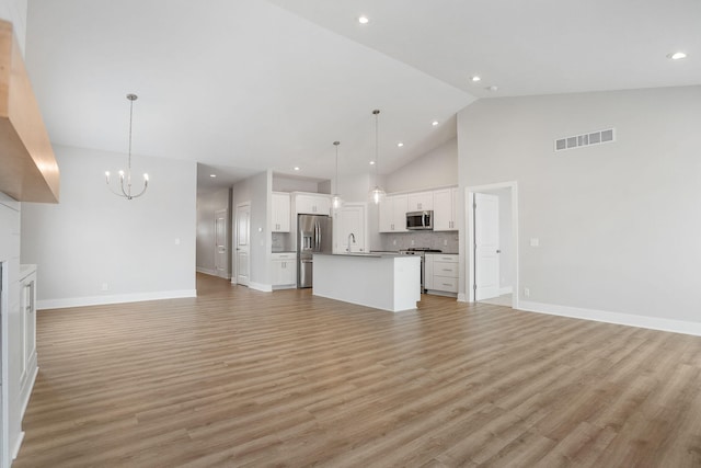 unfurnished living room with sink, a chandelier, high vaulted ceiling, and light hardwood / wood-style floors