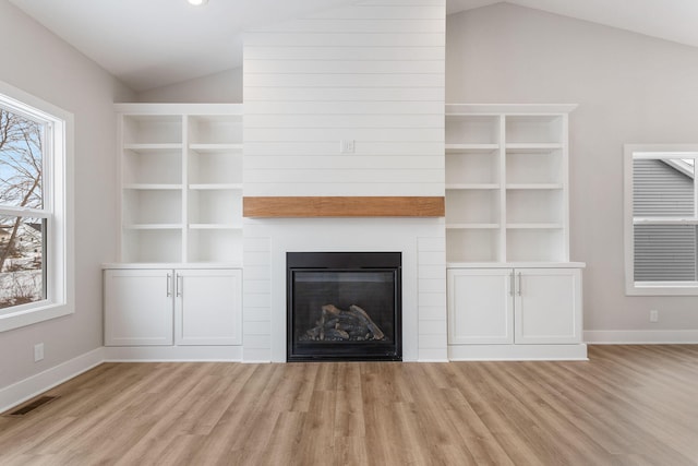 unfurnished living room with vaulted ceiling, a fireplace, and light hardwood / wood-style floors