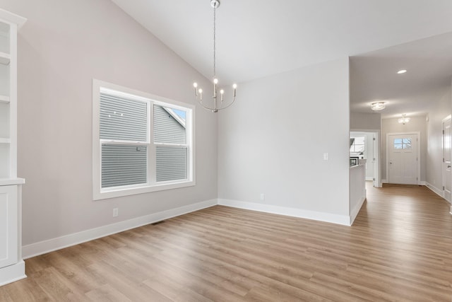 unfurnished dining area featuring lofted ceiling, light hardwood / wood-style flooring, and an inviting chandelier