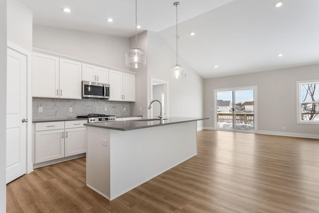 kitchen with a kitchen island with sink, hanging light fixtures, high vaulted ceiling, and white cabinets