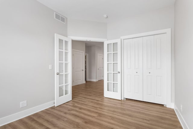 unfurnished bedroom with a closet, hardwood / wood-style floors, and french doors