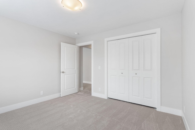 unfurnished bedroom with light carpet and a closet