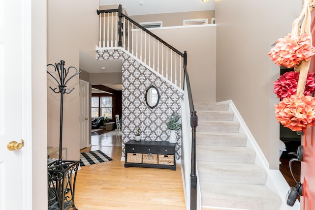 entryway featuring stairway, wood finished floors, and a towering ceiling