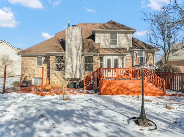 snow covered back of property featuring a wooden deck and central AC unit