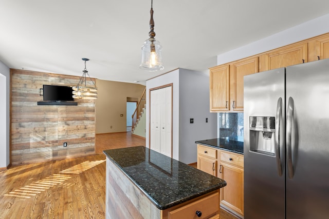 kitchen featuring stainless steel refrigerator with ice dispenser, pendant lighting, dark stone countertops, and light brown cabinets