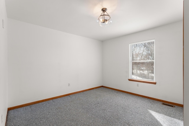 carpeted spare room featuring an inviting chandelier