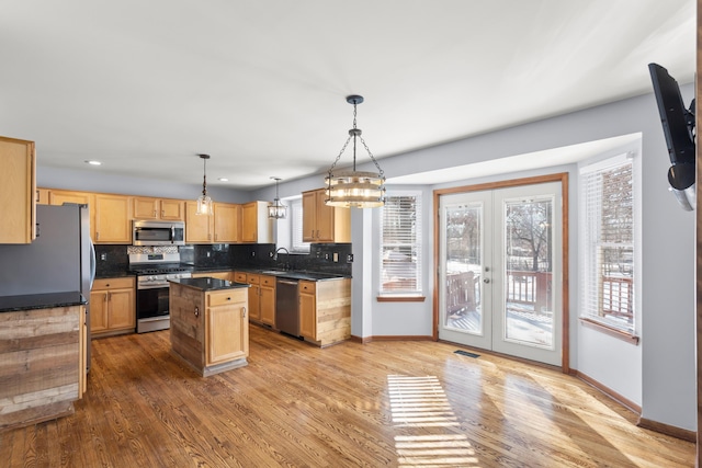 kitchen featuring french doors, a center island, light hardwood / wood-style flooring, pendant lighting, and stainless steel appliances