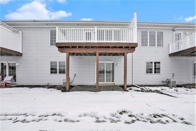 snow covered rear of property featuring central air condition unit