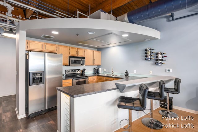 kitchen with light brown cabinetry, sink, kitchen peninsula, and appliances with stainless steel finishes