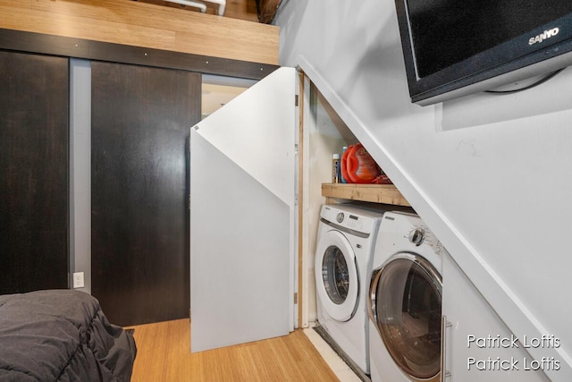 washroom with washing machine and dryer and light hardwood / wood-style floors