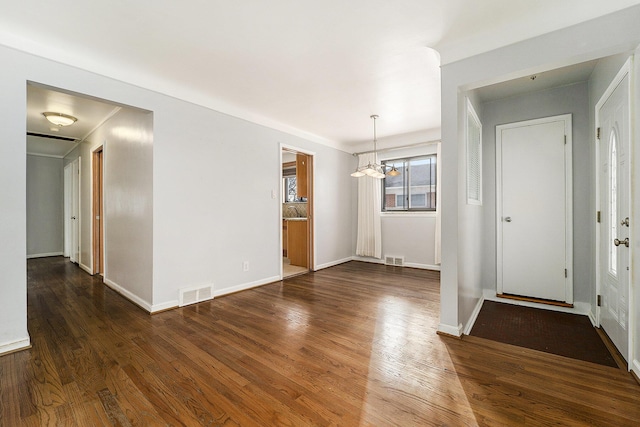 empty room featuring a notable chandelier and dark wood-type flooring