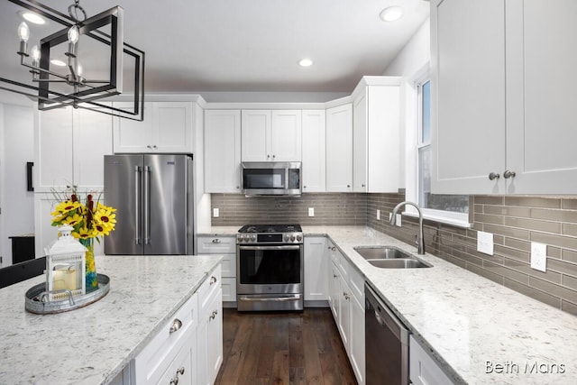 kitchen with sink, decorative light fixtures, white cabinets, and appliances with stainless steel finishes