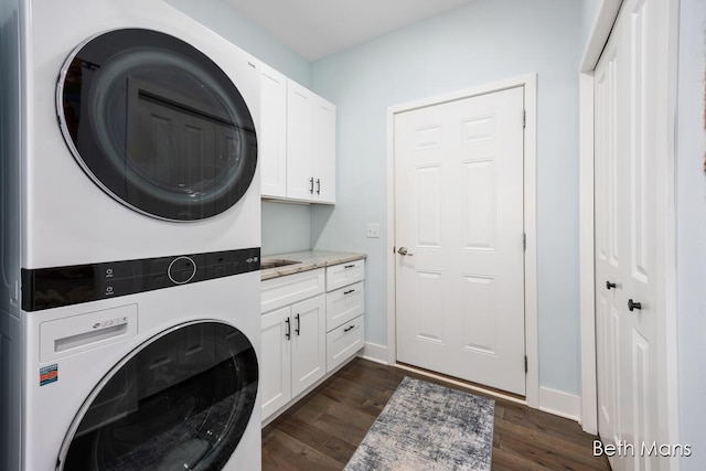 clothes washing area featuring stacked washer / dryer, dark hardwood / wood-style floors, and cabinets